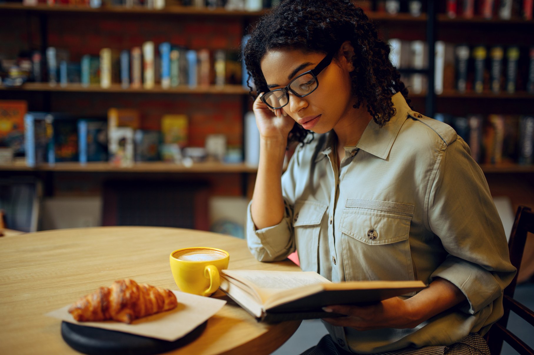 Female Student Reads Book in Library Cafe